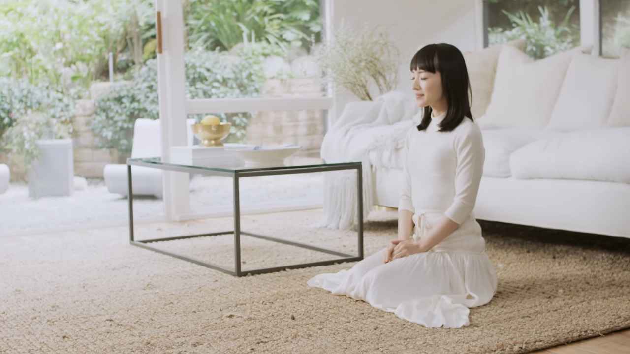 Marie Kondo sits on the floor of a bright, neatly arranged living room.